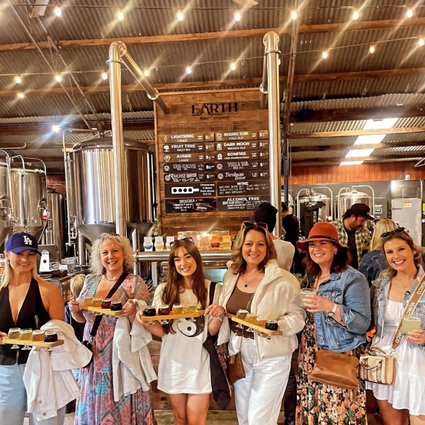 Group of six people holding beer flights at Earth Beer Company brewery.