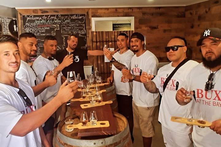 Group of men in a tasting room holding drink tasters, posing for a photo.