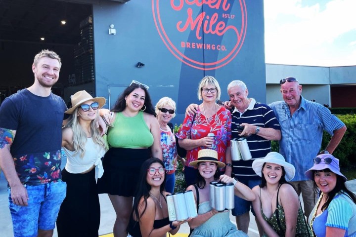Group of people smiling in front of Seven Mile Brewing Co. sign outside the building.