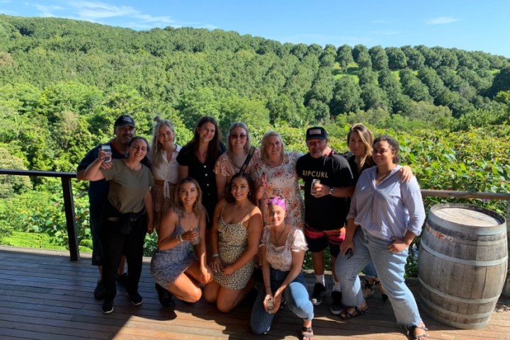 Group of people posing on a deck with scenic green hills in the background.