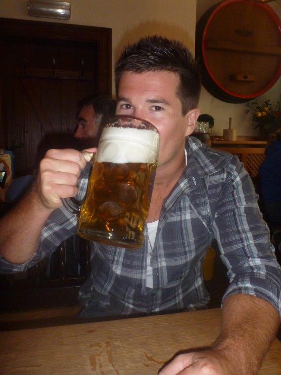 Person in plaid shirt drinking from a large glass of beer.